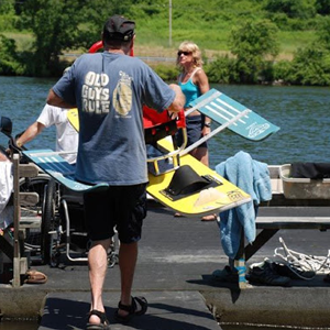 Volunteer carries sitski rig onto dock.